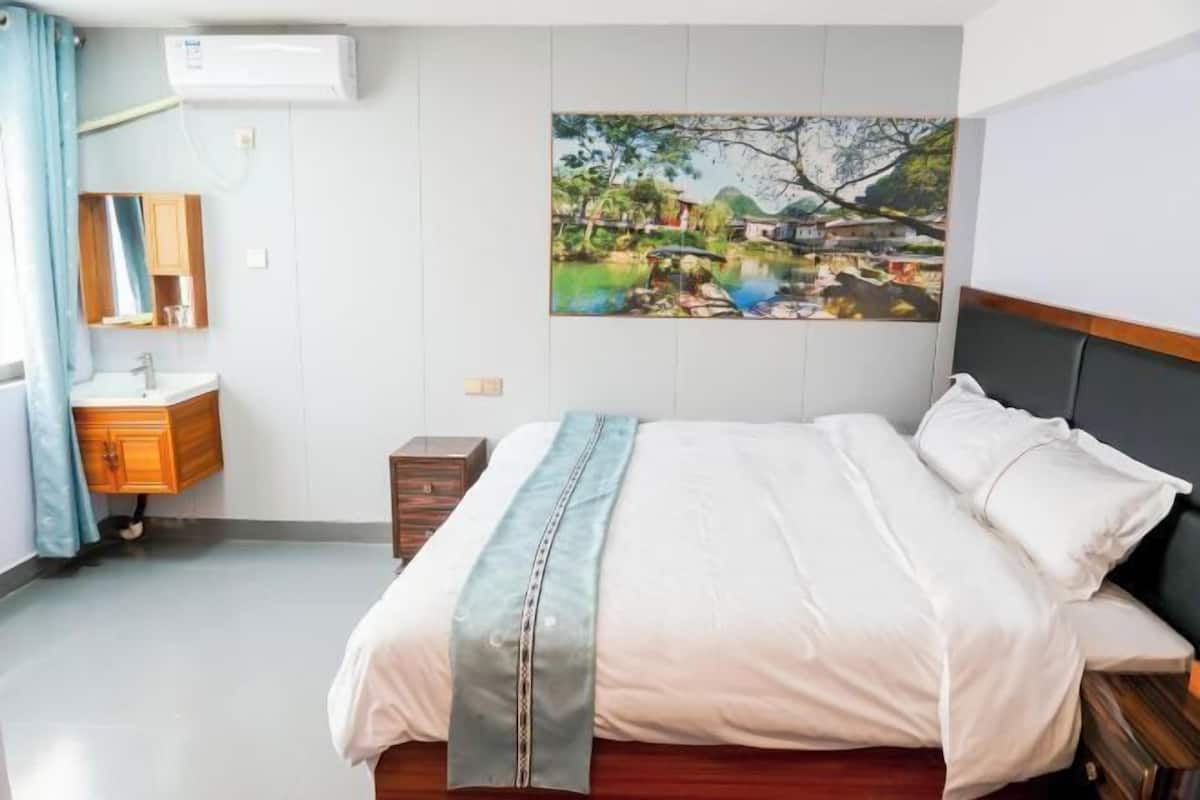 A neatly arranged bedroom with a bed, bedside tables, a mirror, and a painting on the wall.