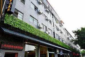 A multi-story building with a flat facade, air conditioning units, and a storefront with signage. - Fenglai Holiday Hostel (Foshan)