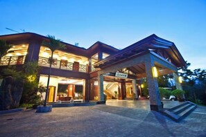 A multi-story hotel with a covered entrance and a well-lit facade. - Yabulun Pastoral Leisure Villa (Baoting)