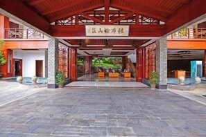 A traditional Chinese architectural entrance with a tiled floor, a wooden roof, and a sign above the entrance.
