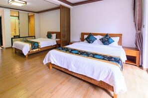 Une chambre d’hôtel avec deux lits simples, un plancher en bois et un grand miroir au mur.