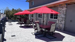 An outdoor patio with stone flooring, red umbrellas, and outdoor seating. - 2 Room Suite - Indoor Pool and Spa - Walk to the Boardwalk (Santa Cruz)
