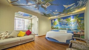 Een kamer met een bed, een bank en een muurschildering van een strand.