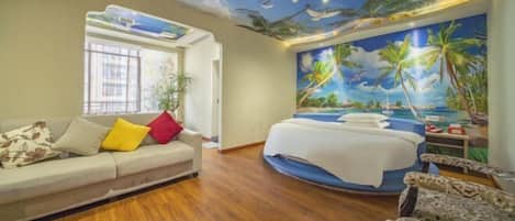 A room with a bed, a sofa, and a ceiling mural depicting a beach scene.