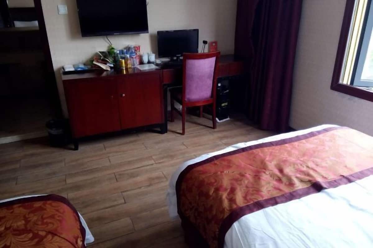 Habitación de hotel con una cama, un escritorio con silla, televisor y ventana con cortinas.