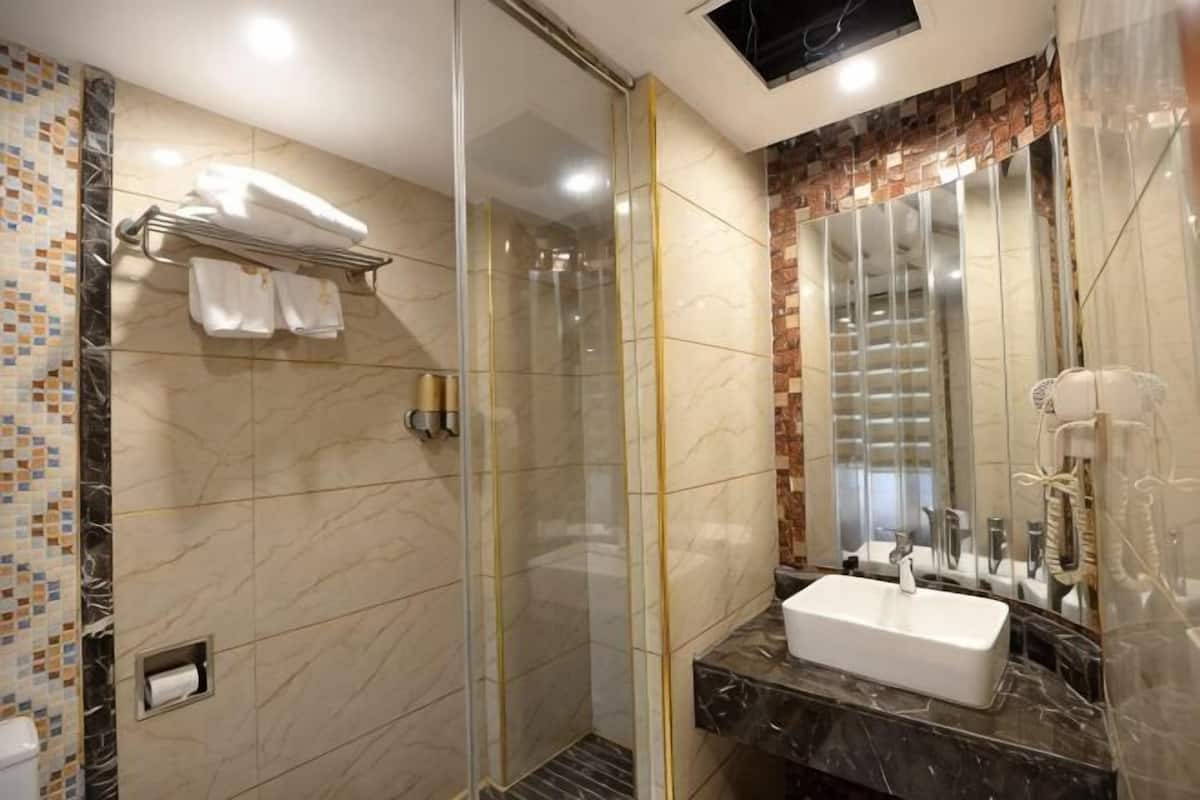 A modern bathroom with a glass-enclosed shower, a marble sink, and a large mirror.