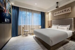 A modern hotel room with a large bed, a small table, a chair, and a TV on the wall. - Yuedu Yizhan Fashion Hotel (Yichun)