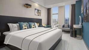Een moderne hotelkamer met een groot bed, uitzicht op de stad, een kaptafel met spiegel, en een zithoek met een stoel en tafel.