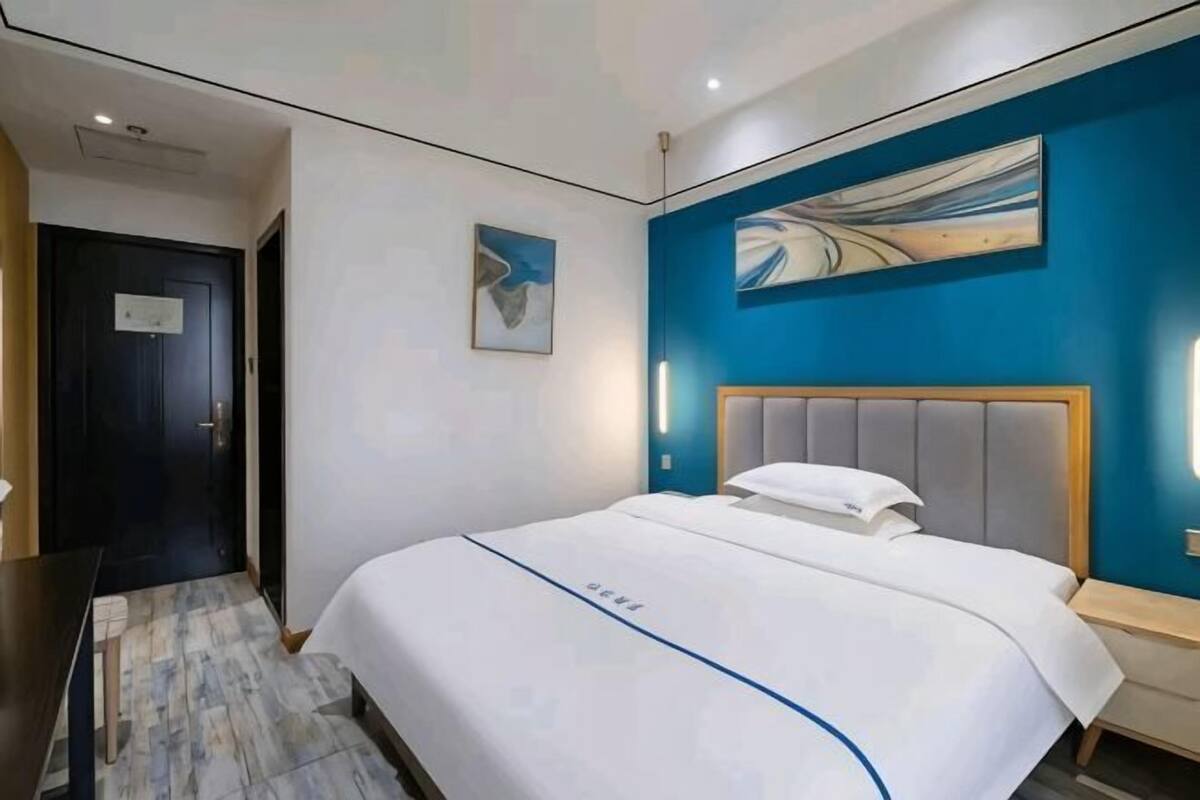 Una habitación de hotel con una cama, un cuadro en la pared y una puerta.