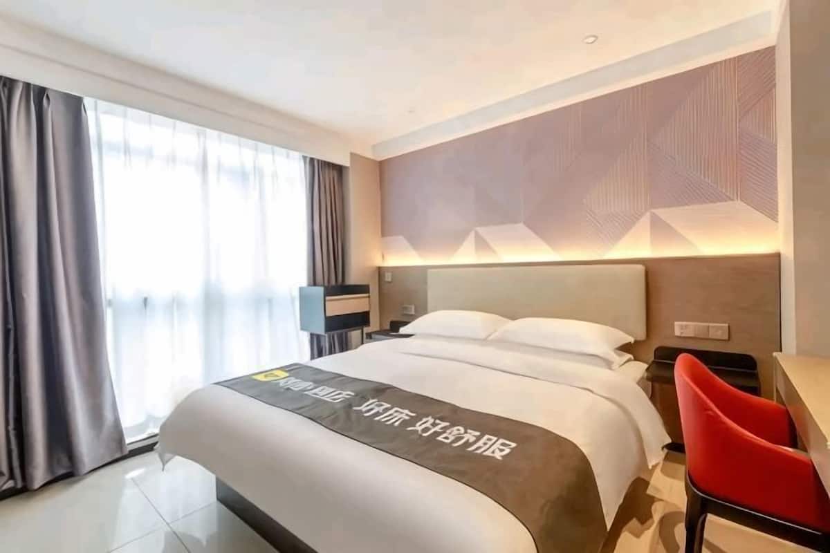 Habitación de hotel con una cama grande, un escritorio y una silla.
