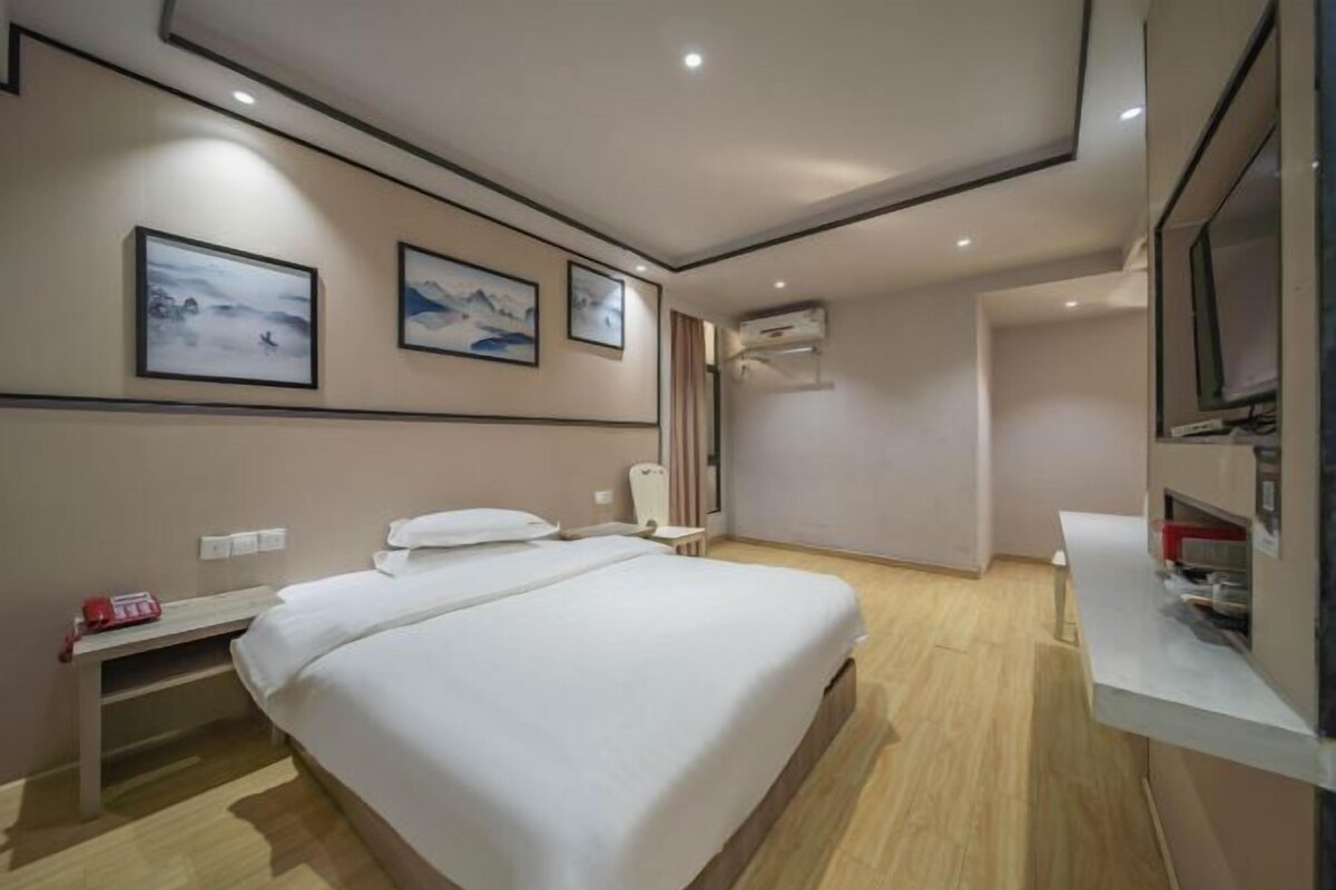 Una habitación de hotel con una cama grande, mesitas de noche, un escritorio y un televisor.