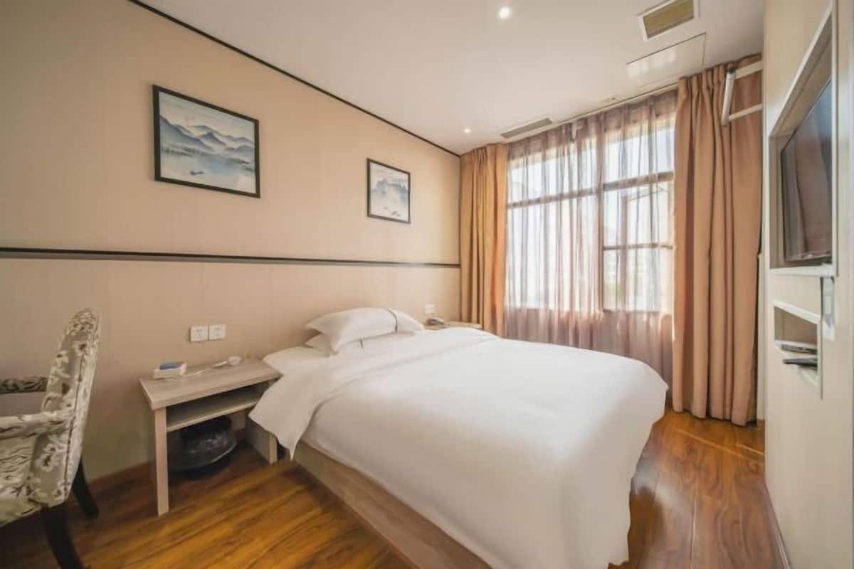 Una habitación de hotel con cama, escritorio, silla y dos cuadros en la pared.