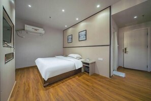 Un dormitorio con cama, mesita de noche y aire acondicionado instalado en la pared.