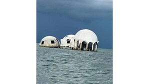 Three white domed structures on a body of water.