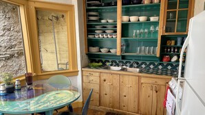 A compact kitchen with a glass table, blue chairs, and a tiled backsplash. - Boho Hip Bungalow (Bisbee)