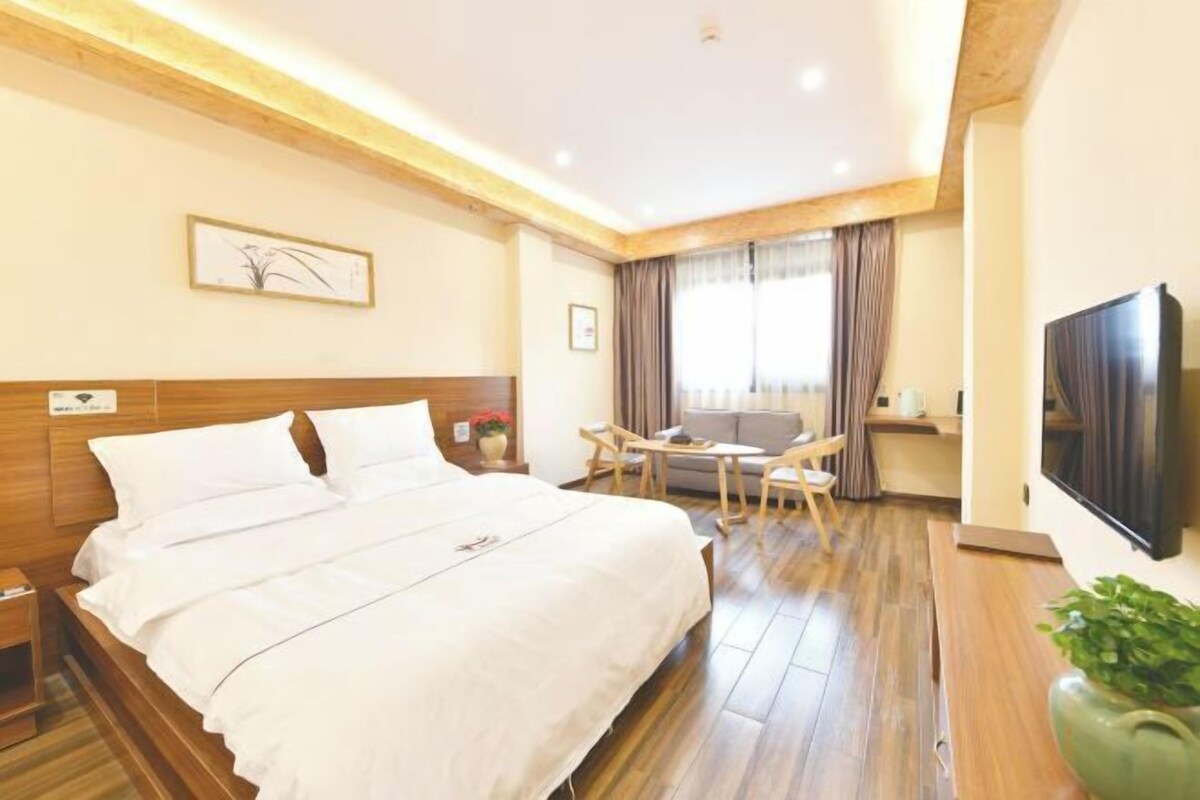 Quarto de hotel com uma cama grande, uma escrivaninha e uma televisão.