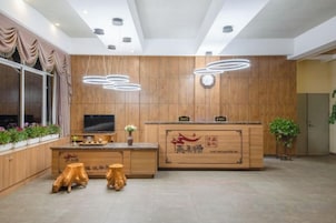 Una moderna zona de recepción con un mostrador de madera, un televisor de pantalla plana y una planta en maceta.