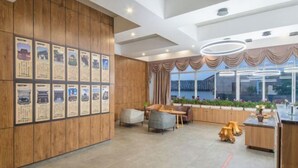 A modern hotel lobby with wooden paneling, a reception desk, seating area, and large windows offering views of the outside. - Yanchaoyang Boutique Inn (Jianshui)