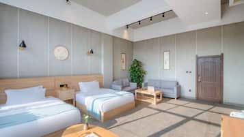 Quarto de hotel moderno com duas camas, um sofá, uma mesinha e uma janela grande.