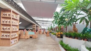 A covered walkway with bookshelves on one side and potted plants on the other. - Yanchaoyang Boutique Inn (Jianshui)