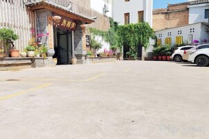 Um edifício com entrada tradicional, plantas em vasos e área de estacionamento bem definida.