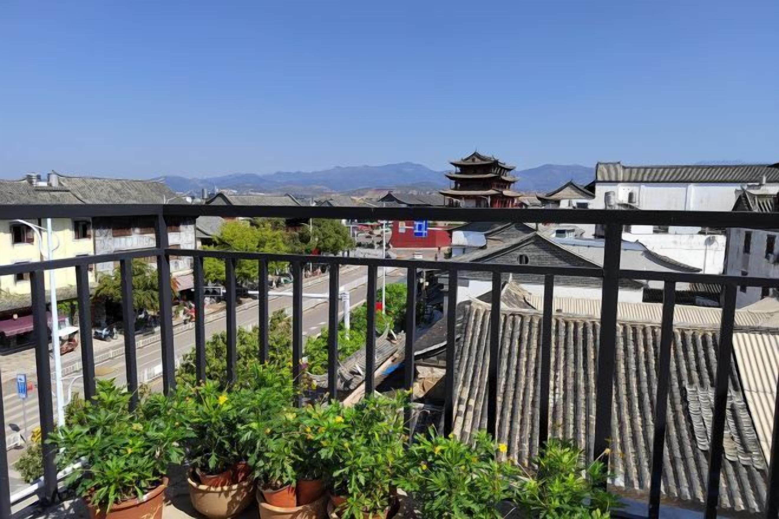 Un balcón con plantas en macetas, edificios tradicionales y un cielo despejado.