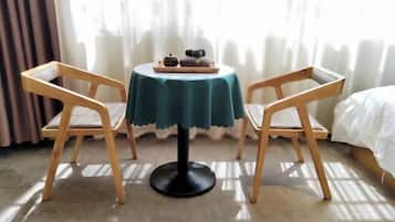 A small round table with a teal tablecloth, two wooden chairs, and a tray with a teapot and cups.