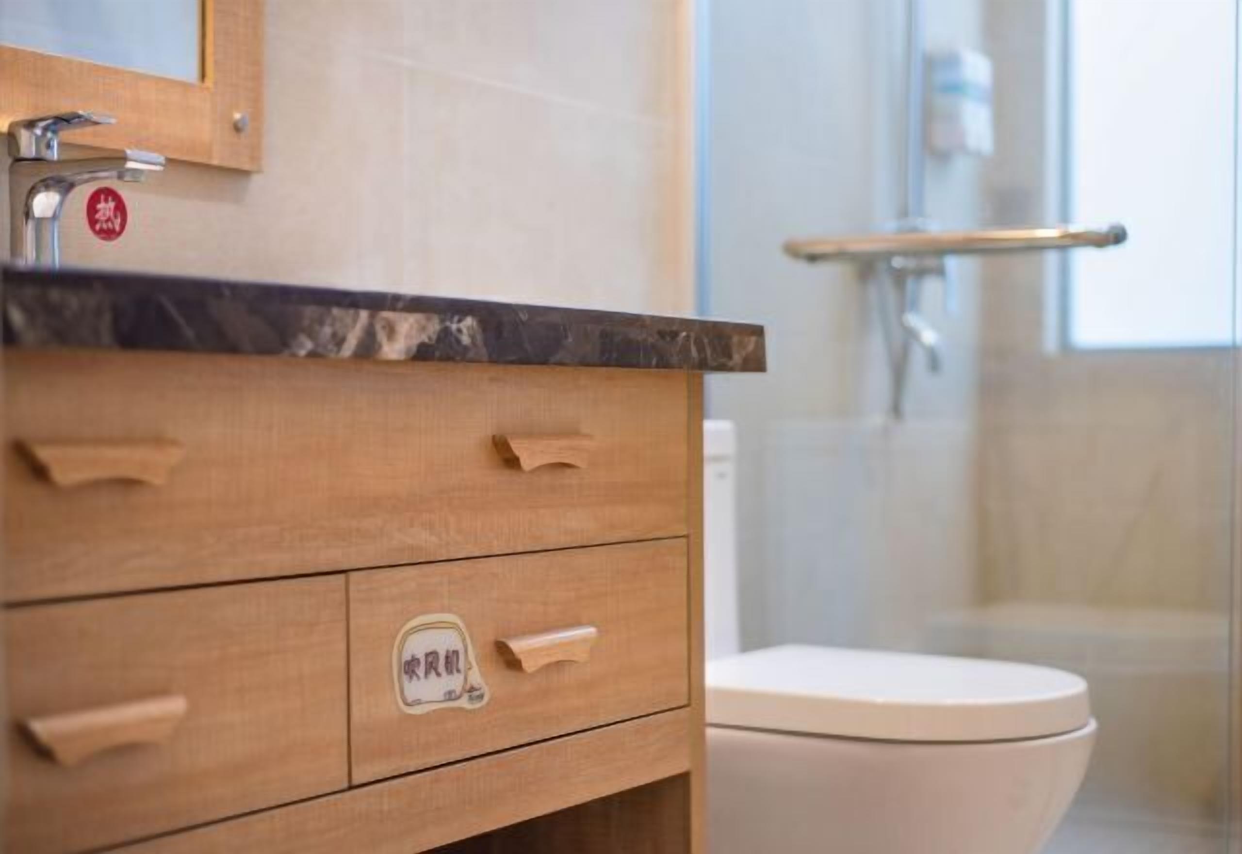 A bathroom with a wooden vanity, a white toilet, and a glass shower enclosure.