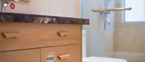 A bathroom with a wooden vanity, a white toilet, and a glass shower enclosure.