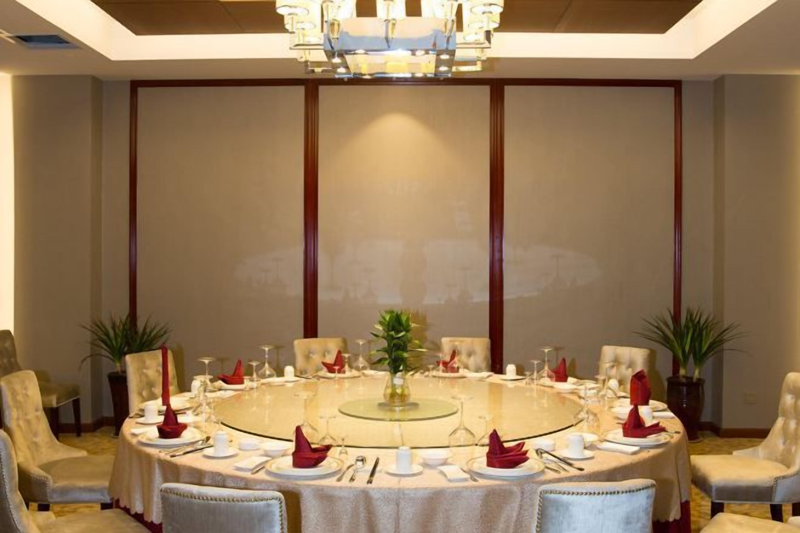 A round table with chairs, a chandelier, and a plant centerpiece.