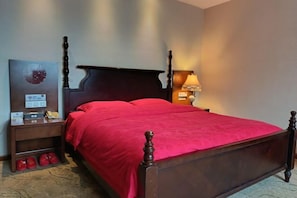 A bed with a headboard, a nightstand with a lamp, and a wall-mounted clock.