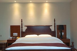 A four-poster bed with a wooden headboard, two bedside tables, and a nightstand with a lamp. - Junteng Hotel (Jinan)
