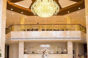 A hotel lobby with a grand chandelier, marble flooring, and a statue. - Junteng Hotel (Jinan)