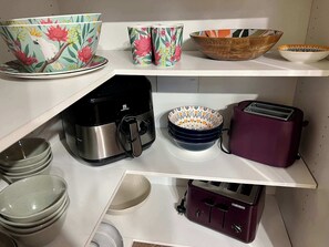 A kitchen with various appliances and utensils, including a coffee maker, toaster, and bowls.