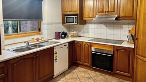 Une cuisine avec des meubles en bois, un four à micro-ondes, une cuisinière et un lave-vaisselle.