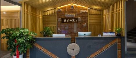 A reception desk with a wooden slatted roof, a brick wall, and a nameplate.