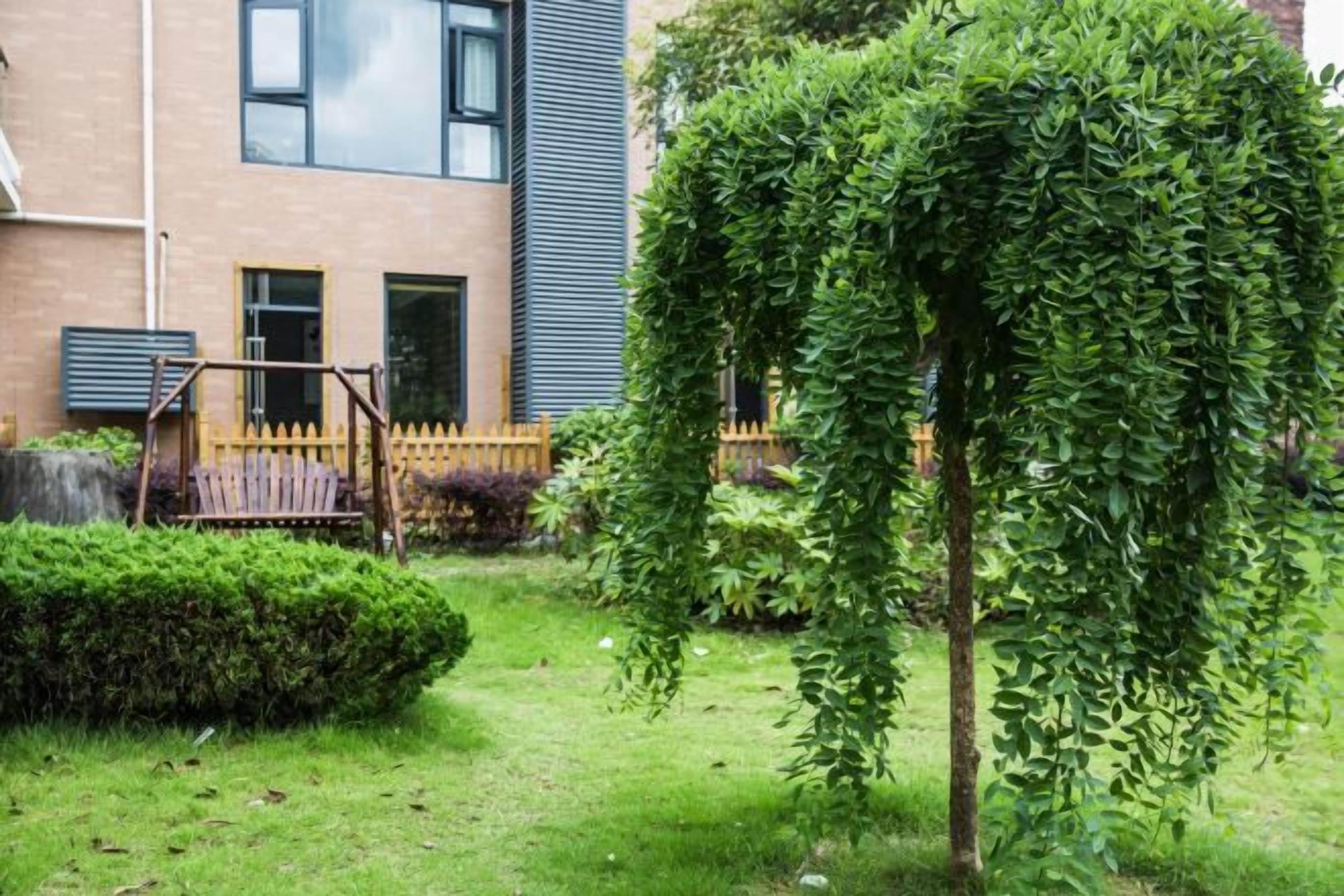 A residential building with a well-maintained garden, a swing set, and a wooden fence.