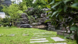 A stone pathway leading to a stone wall with greenery around. - Yueming Xiaoyuan Hostel (Wuyishan)