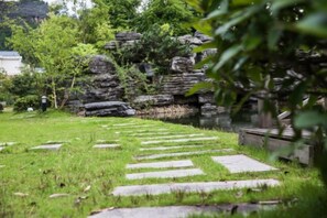 A stone pathway leading to a natural area with rocks and greenery.