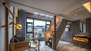 A modern interior with a staircase, a wooden bench, a table with a plant, and a bathroom with a sink and mirror. - Yueming Xiaoyuan Hostel (Wuyishan)