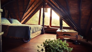A cozy attic bedroom with a bed, a small desk, and a window. - La Cabaña Musical (Medellín)