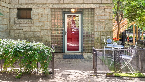 Un edificio de piedra con puerta roja, una ventana pequeña y una reja de metal.