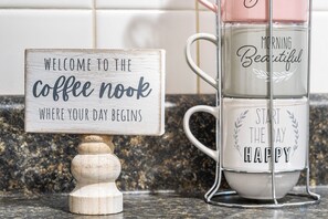 A coffee maker with a sign that reads "Welcome to the coffee nook where your day begins."