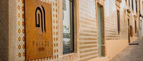A building with a patterned facade, a sign reading "PORTALEGRE PALACE," and a street lamp.