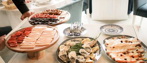 A buffet table with various food items including meats, cheeses, and seafood.