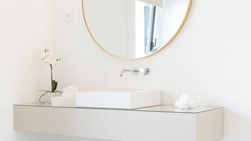 A modern bathroom with a round mirror, white sink, and marble floor.