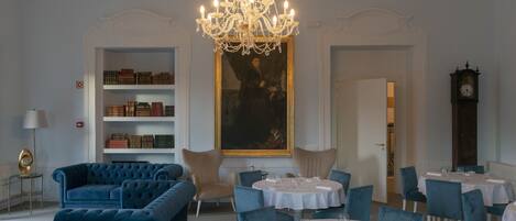 Un espace repas avec des tables rondes, des canapés bleus et un lustre.