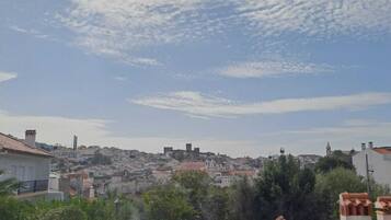 Terrat amb teules de terracota, vista llunyana d'una vila amb edificis històrics, i un cel amb nuvolades disperses.