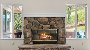 A stone fireplace with a glass front, flanked by windows. - Between Napa & San Francisco 6bed 4bath Clean (Concord)