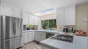A modern kitchen with white cabinets, stainless steel appliances, and a large window providing a view of the outdoors. - Between Napa & San Francisco 6bed 4bath Clean (Concord)